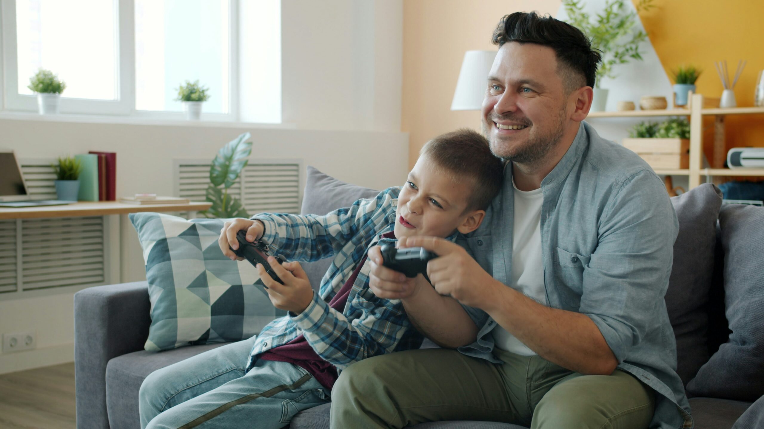 ソファに並んでゲームを楽しむ父と息子｜子どものゲーム時間は禁止せず一緒に楽しむ
